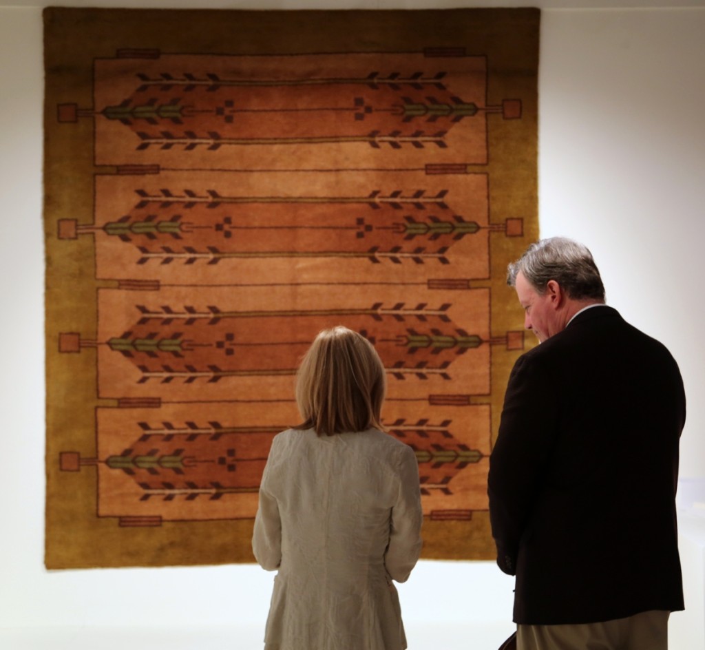 Two attendees stand in front of a carpet by Frank Lloyd Wright in the booth of Bernard Goldberg Fine Arts, New York City.
